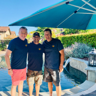Three men enjoy smiling in front of the pool